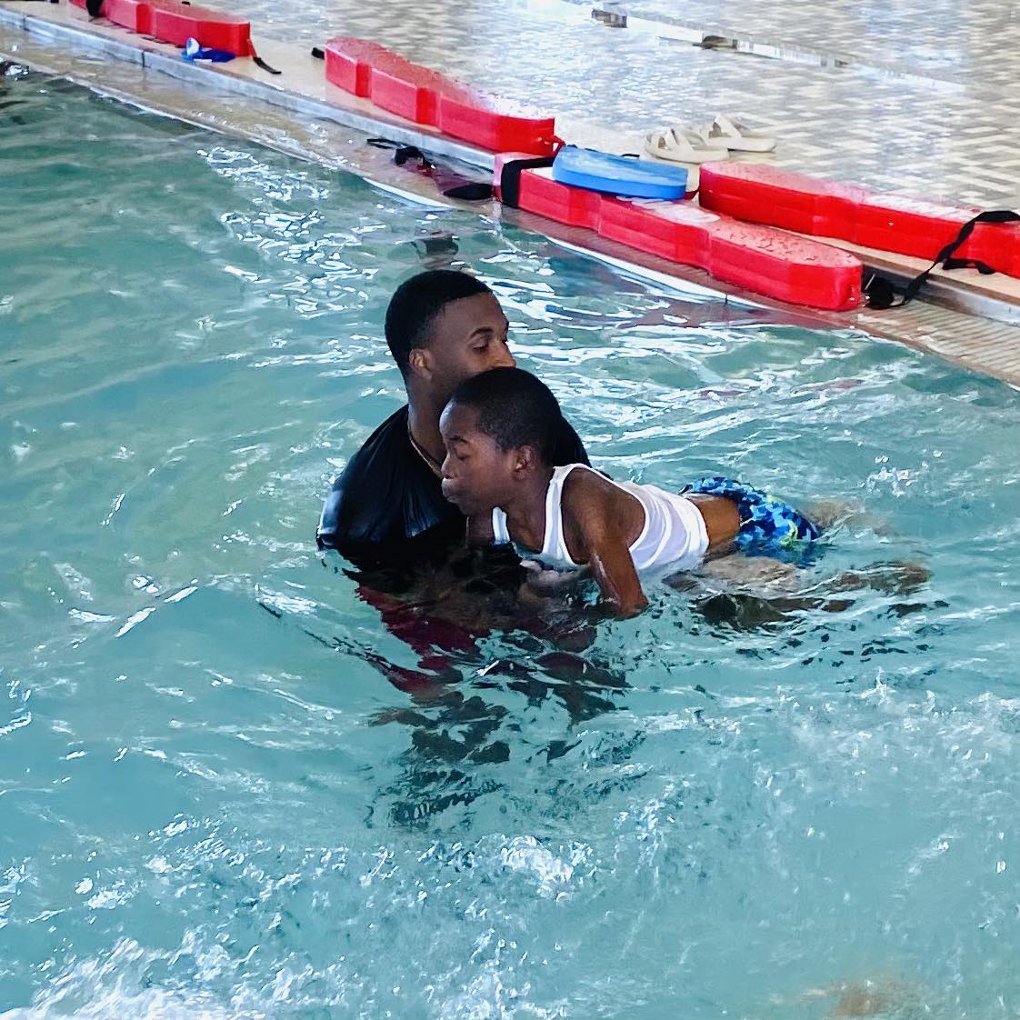 A man helping a boy swim.